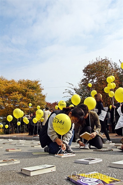 이날 기자회견에 참석한 한 학생이 역사교과서 국정화 반대 메시지를 적은 노란 풍선에 끈을 매달아 역사책과 연결하고 있다.