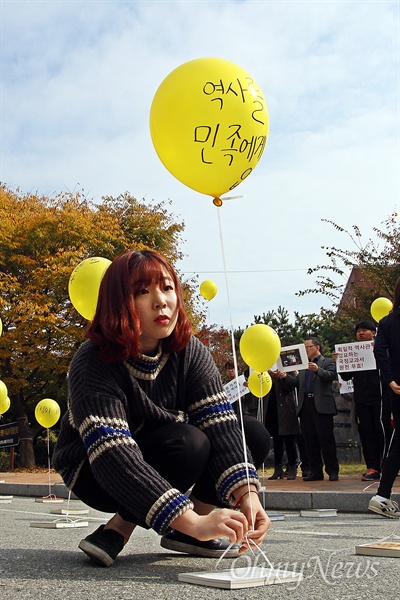 이날 기자회견에 참석한 한 학생이 역사교과서 국정화 반대 메시지를 적은 노란 풍선에 끈을 매달아 역사책과 연결하고 있다.