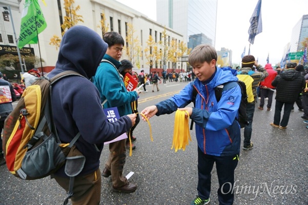 '11.14 민중 총궐기 대회'가 열린 14일 오후, 서울 중구 한국프레스센터 앞에서 참가자들이 세월호 참사를 잊지 말자며 노란띠를 나눠주고 있다.