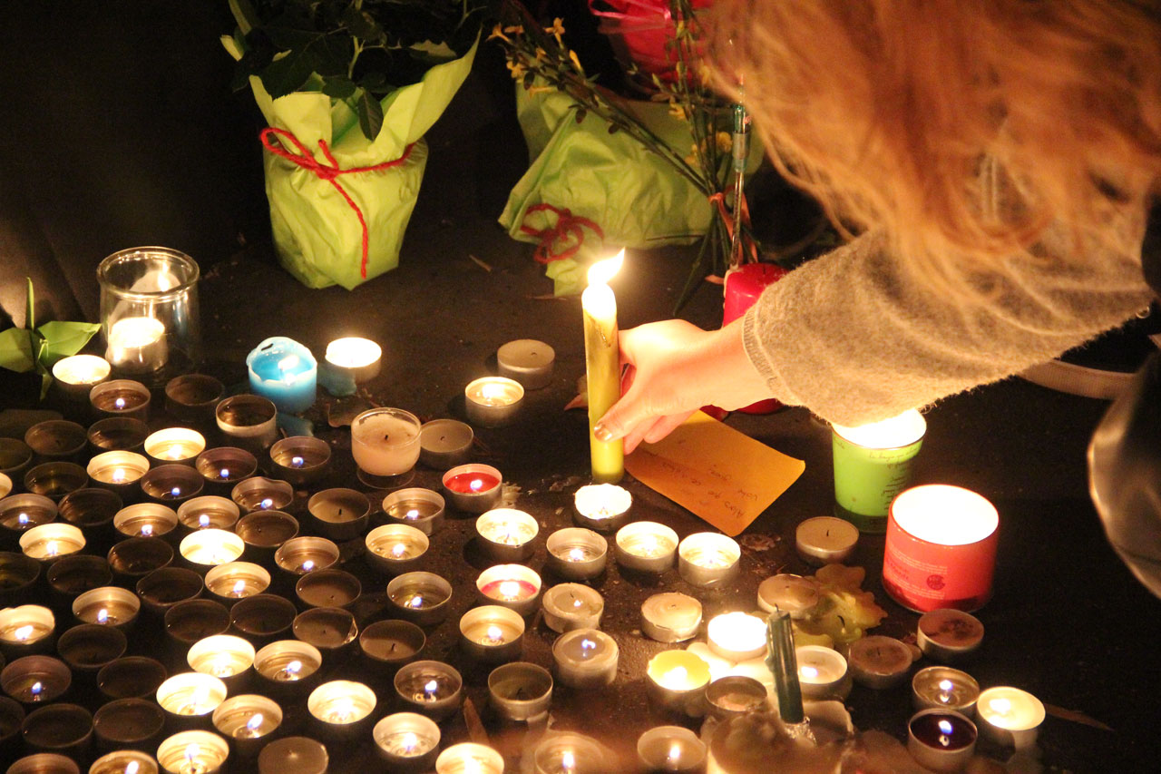 한 여성이 샤론느 길 앞에서 희생자를 추모하기 위해 촛불을 불을 붙여 세우고 있다. 