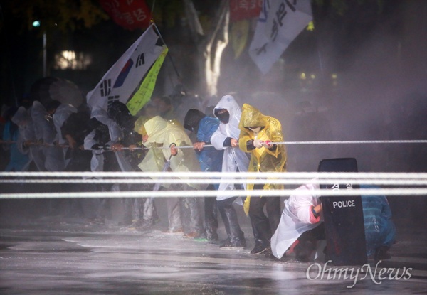 민중총궐기 대회가 열린 2015년 11월 14일 오후 종로1가 종로구청입구 사거리에서 집회참가자들이 밧줄을 이용해 차벽을 쌓고 있는 경찰버스를 끌어내려하자, 경찰이 캡사이신 물대포를 발사하고 있다.