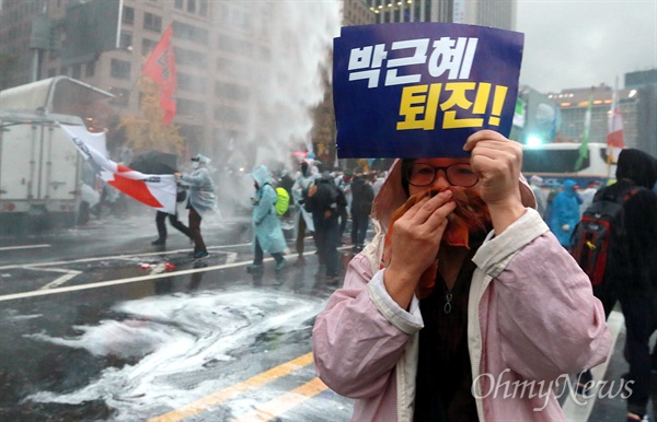 경찰, 민중총궐기 대회 참가자향 캡사이신 난사 14일 오후 서울 중구 청계광장 앞에서 경찰이 '민중총궐기 대회' 참가자들을 향해 캡사이신 물대포를 난사하자, 한 시민이 박근혜 정권 퇴진을 요구하는 피켓을 들어보고 있다.