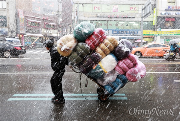 폭설 쏟아지는 남대문시장 서울에 올겨울 첫 대설주의보가 발령된 3일 오전 남대문시장에서 한 시민이 폭설을 뚫고 수레 가득 물건을 실어 배달하고 있다. 