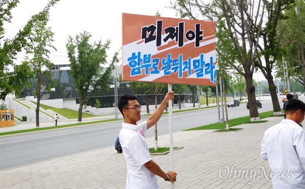  한 학생이 구호가 적힌 피켓을 들고 평양 시내를 활보하고 있다.