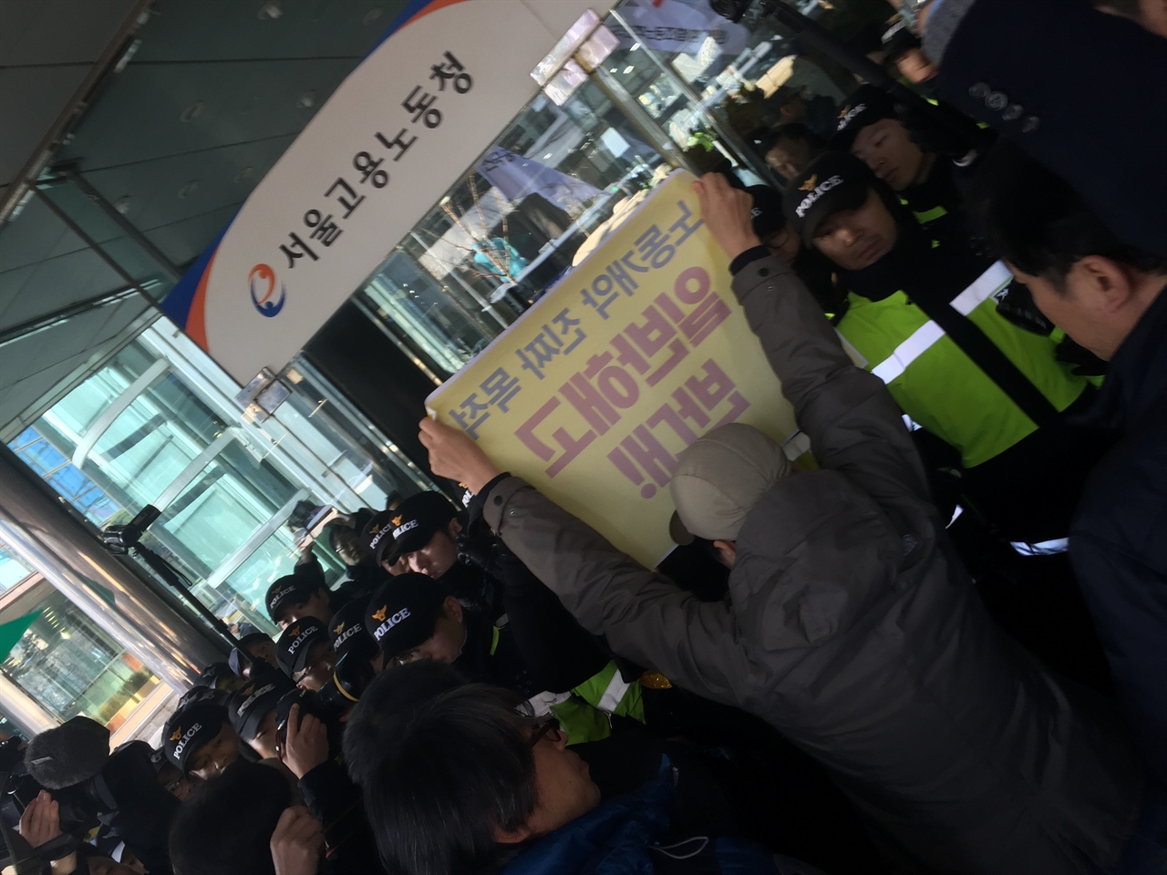 민주노총 정혜경 부위원장이 현수막을 들고 들어가게 해줄 것을 요구하고 있다.