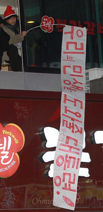 2012년 12월 17일, 경기도 광명 철산동 문화의 거리에서 열린 박근혜 당시 새누리당 대선후보 유세에서 한 지지자가 유리 창문 넘어 '우리의 민생을 도와줄 대통령'이라고 적힌 응원 문구를 펼쳐보이고 있다.
