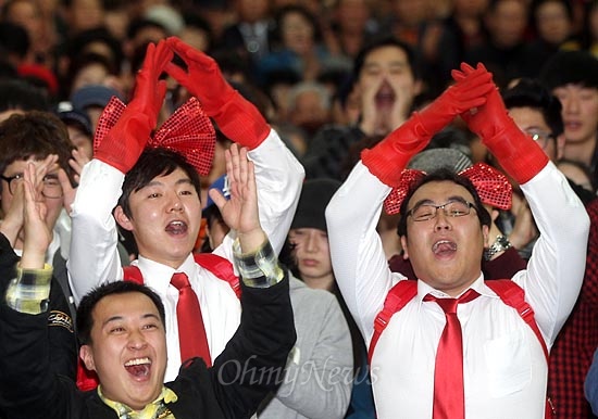 2012년 11월 13일, 대전 탄방동 오페라웨딩컨벤션센터에서 열린 '대전희망살리기 전진대회'에서 고무장갑, 넥타이, 머리리본, 가방을 빨간색으로 맞춘 청년들이 인솔자의 신호에 맞춰 "박근혜, 박근혜"를 연호하고 있다.