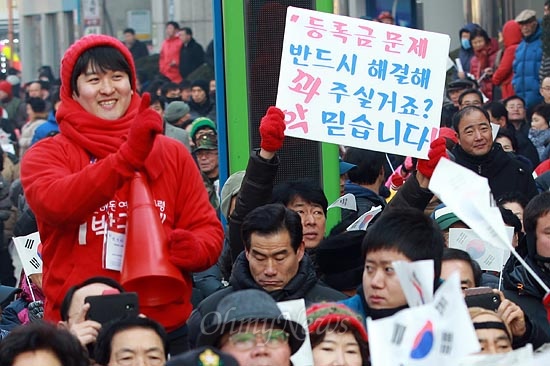 2012년 12월 13일, 경기도 의정부 의정부동 이성계 동상 앞에서 열린 박근혜 당시 새누리당 대선 후보 유세에서 한 유권자가 "등록금 문제 반드시 해결해 줄거라고 믿는다"는 피켓을 들어보이고 있다.
