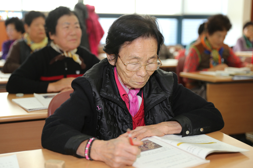광양노인복지관에서 열리는 초등학력인정 문자해득 과정에 다니는 어르신이 연필을 들고 책을 보고 있다. 지난 12월 9일의 모습이다.