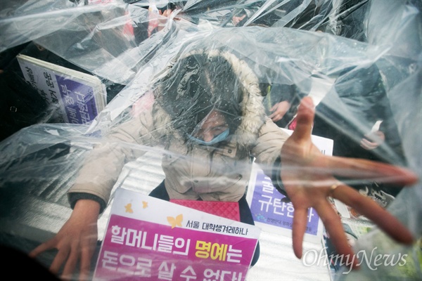 지난 달 30일 오후 서울 종로구 일본대사관 앞에서 평화나비 네트워크 등 대학생들이 비를 맞으며 평화의 소녀상 비를 맞으며 주변 자리를 지키고 있다.
