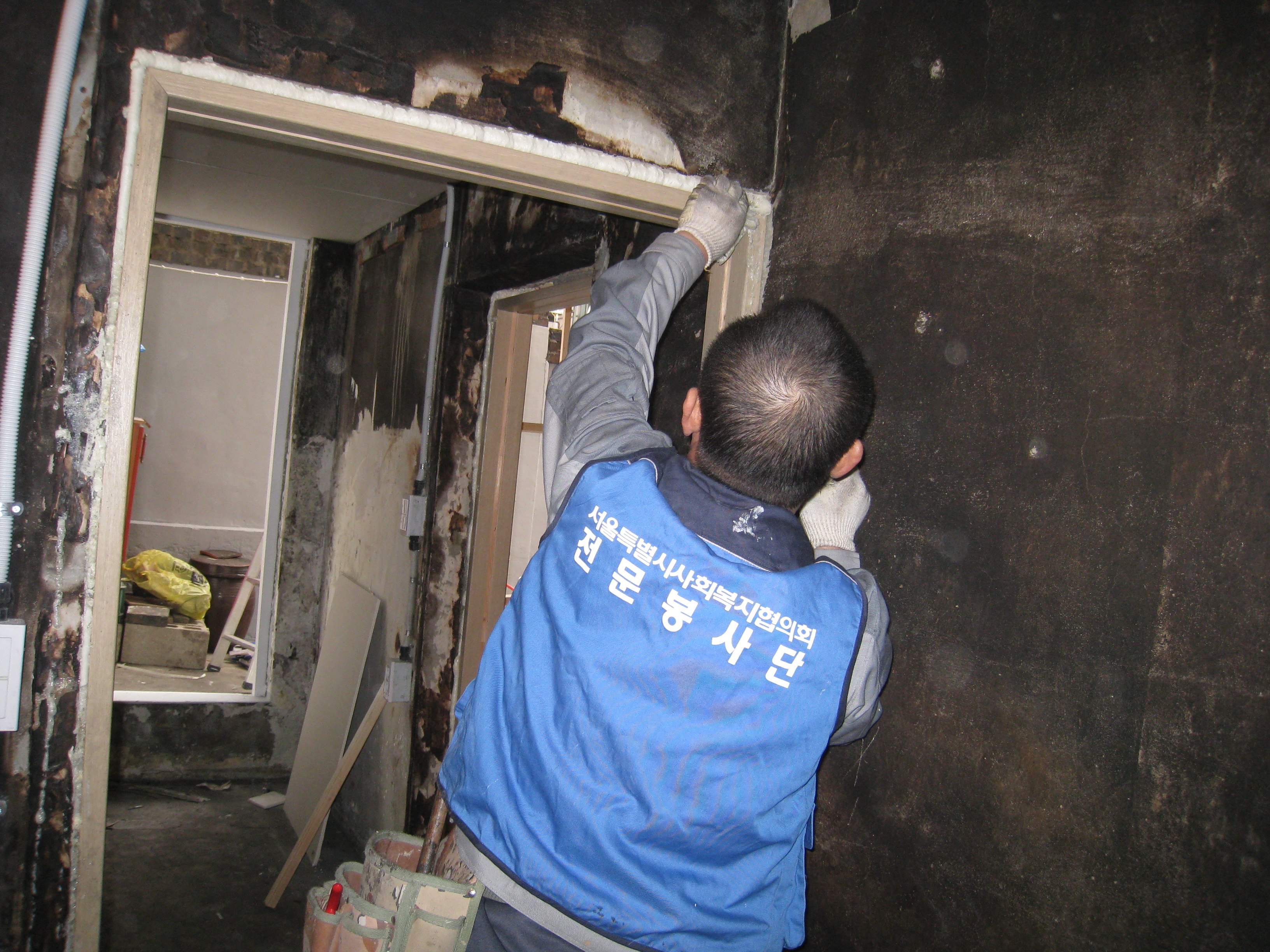 집수리봉사단 단원이 불에 타버린 집을 수리하고 있다.