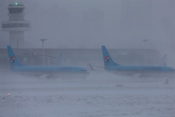 최강 한파로 제주공항에서 항공기 운항이 잠정 중단된 24일 오전 강한 눈발에 가려 항공기들이 희미하게 보이고 있다.