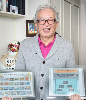 송문호씨가 주제별로 재구성해 만든 우표액자들을 들고 환하게 웃고 있다. 