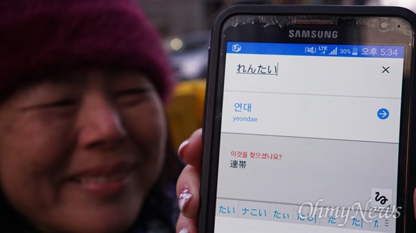 1월 27일 오후 서울 종로구 평화의 소녀상 옆에서 일본인 나가미네 미나꼬(61)씨가 스마트폰에 '연대'를 써 보이고 있다.