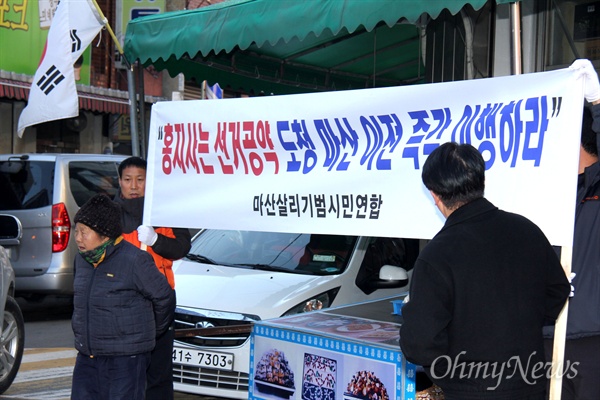  마산살리기범시민연합 회원들이 1일 오후 창원시 마산회원구 소재 동마산시장 앞에서 홍준표 지사를 비난하는 펼침막을 들고 서 있다.