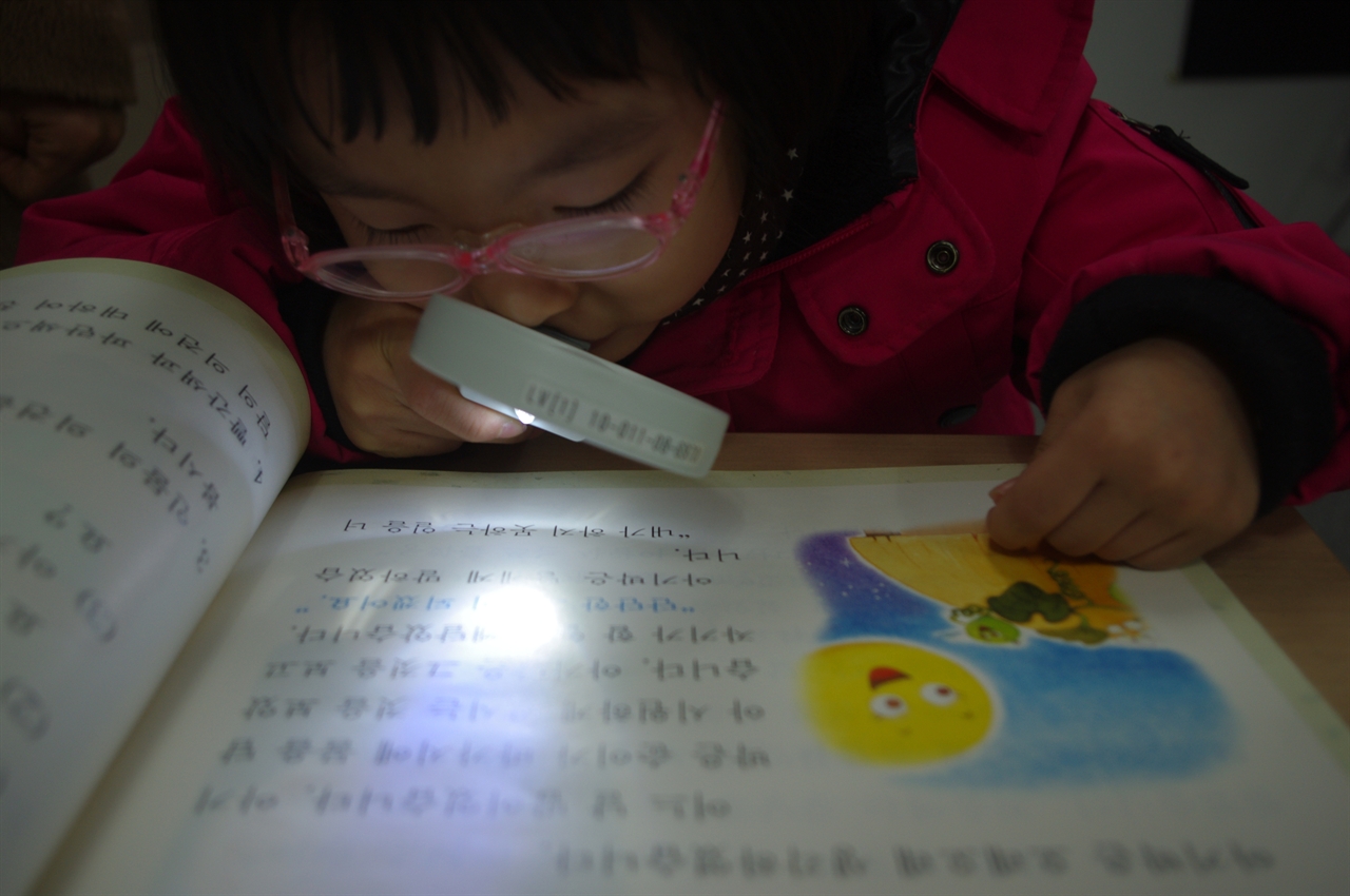 고배율 확대경과 밝은 빛으로 책읽기에 도움을 줄 수 있는 도구