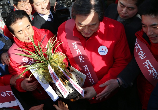 5일 설 연휴를 맞아 부산을 찾은 김무성 새누리당 대표가 한 시민으로부터 '국정교과서 철회, 세월호 진상규명'이라고 적힌 리본이 달린 난 선물을 받고 있다.