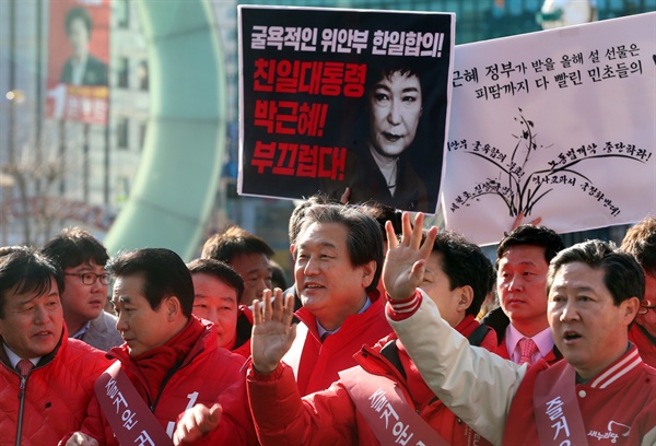 김무성 대표 등 새누리당 인사가 5일 오후 부산역에서 고향을 찾는 시민에게 인사하는 가운데 정의당 회원이 박근혜 대통령의 한일 위안부 합의를 비판하는 피켓 시위를 벌이고 있다.