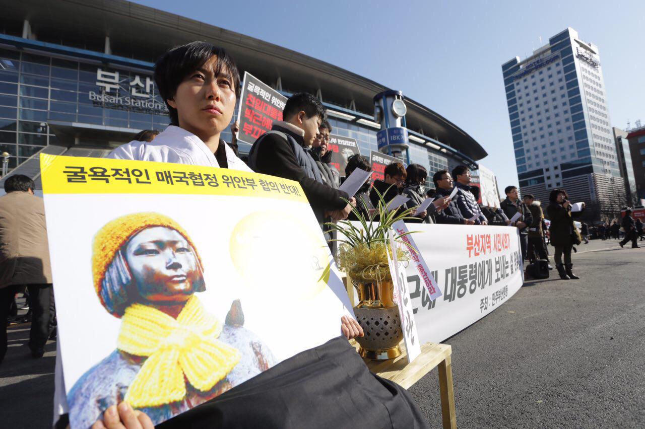 민주부산행동이 주최한 '박근혜 대통령에게 드리는 설날 선물(민란)'기자회견장에서 위안부'소녀상'복장을 한 대학생이 '민란'화분과 함께 앉아있다.