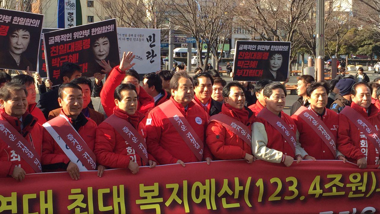 김무성대표가 설날인사를 하는 중에 시민단체회원이 박근혜대통령이 부끄럽다는 내용의 피켓을 들고 함께 하고 있다