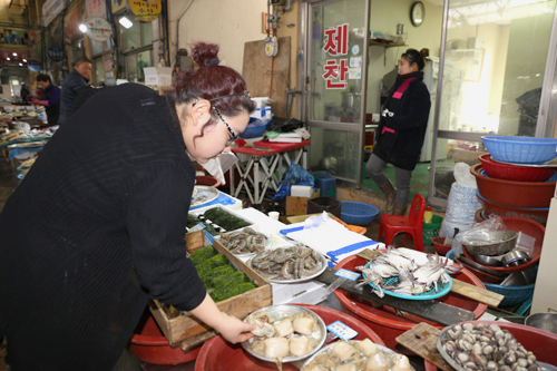 윤지아 씨가 자신의 가게 옆 수산물 가게에서 식재료를 고르고 있다. 그녀는 식재료 대부분을 시장 안에서 산다.