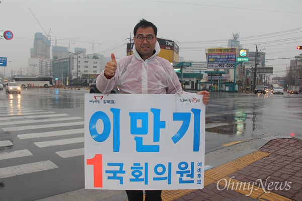'김해을' 국회의원 선거에 나선 새누리당 이만기 후보가 18일 아침 비가 내리는 속에 김해 장유1동사무소 앞 거리에서 비옷을 입고 출근인사하고 있다.