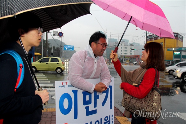 '김해을' 국회의원 선거에 나선 새누리당 이만기 후보가 18일 아침 비가 내리는 속에 김해 장유1동사무소 앞 거리에서 비옷을 입고 출근인사하면서 지나가는 시민들과 이야기를 나누고 있다.