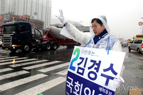  '김해을' 국회의원 선거에 나선 더불어민주당 김경수 후보가 18일 아침 비가 내리는 속에 김해 내외동사거리에서 비옷을 입고 출근인사하고 있다.
