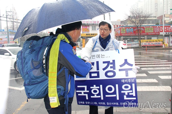 '김해을' 국회의원 선거에 나선 더불어민주당 김경수 후보가 18일 아침 비가 내리는 속에 김해 내외동사거리에서 비옷을 입고 출근인사하면서 지나는 시민과 이야기를 나누고 있다.
