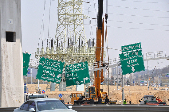 충남 아산시에서 천안시로 이어지는 왕복 8차선 도로에 설치된 표지판이 꺾이며 도로 위에 위태롭게 걸쳐져 있다. 