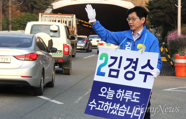 '김해을' 제20대 국회의원선거 더불어민주당 김경수 후보가 1일 오후 창원터널 입구에서 "오늘 하루도 수고하셨습니다"는 팻말을 목에 걸고 지나는 차량을 향해 손을 흔들며 인사하고 있다.