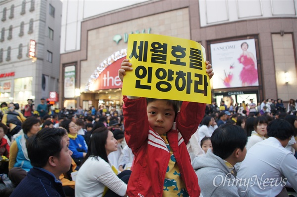 세월호참사 2주기 대구시민문화제에 참석한 한 어린이가 '세월호를 인양하라'는 손팻말을 들어보이고 있다.