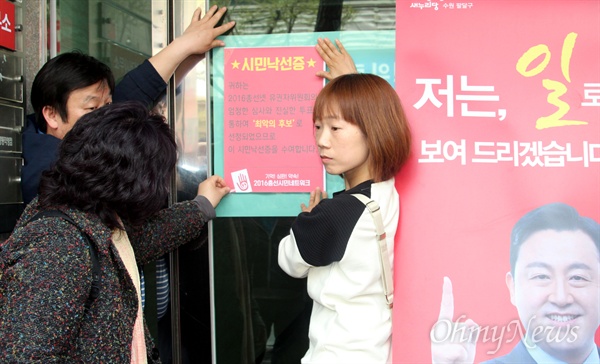 시민 낙선증을 김용남 후보 사무소가있는 건물 현관 유리문에 붙이고 있는 모습