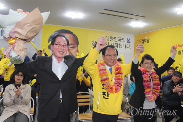 '창원성산' 국회의원선거에서 당선한 정의당 노회찬 후보가 13일 저녁 선거사무소에서 꽃다발을 받은 뒤 부인 김지선씨, 권영길 전 민주노동당 대표와 함께 손을 들어 인사하고 있다.