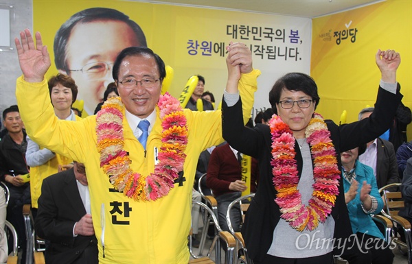 '창원성산' 국회의원선거에서 당선한 정의당 노회찬 후보가 13일 저녁 선거사무소에서 부인 김지선씨와 꽃다발을 받은 뒤 손을 들어 보이고 있다.