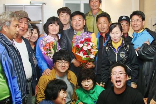 논산시의원 라 선거구 재선거에 출마한 더불어민주당 김만중 후보가 당선소식을 들은뒤 지지자에게 축하의 꽃다발을 받고 기뻐하고 있다