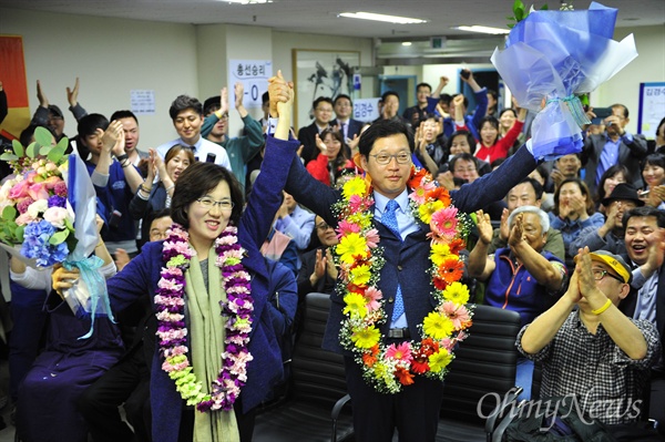 더불어민주당 김경수 당선인(김해을)이 13일 저녁 당선이 확정된 뒤 부인과 함께 꽃다발을 받아들고 환호하고 있다.