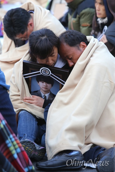 지난 5월 9일, 세월호 참사 희생자 유가족들이 박근혜 대통령 면담을 요구하며 청와대 입구에서 밤샘 노숙을 한 가운데 한 부모가 아들의 영정사진을 껴안고 잠들어 있다.