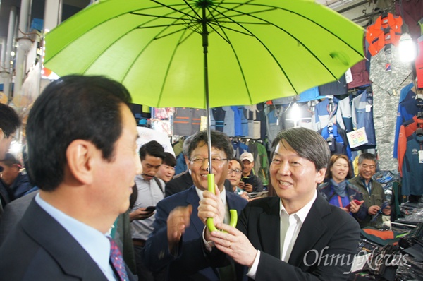 안철수 국민의당 상임대표가 19일 오후 대구 서문시장을 방문하자 많은 시민들이 환영한 가운데 한 시민이 연두색 우산을 씌워주자 안 대표가 즐거워하고 있다.