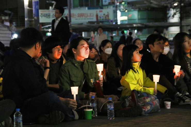촛불집회 참석자들이 신원영군 추모 영상을 지켜보며 안타까워하고 있다. 
