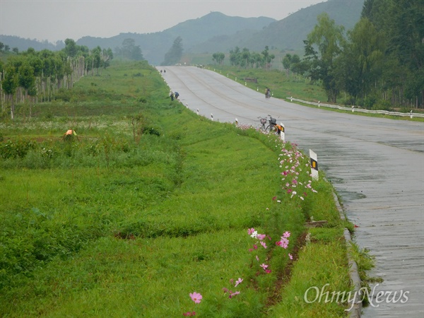 평원(평양-원산) 고속도로 풍경. 비가 내리자 사람들이 나타나 밭을 일군다.