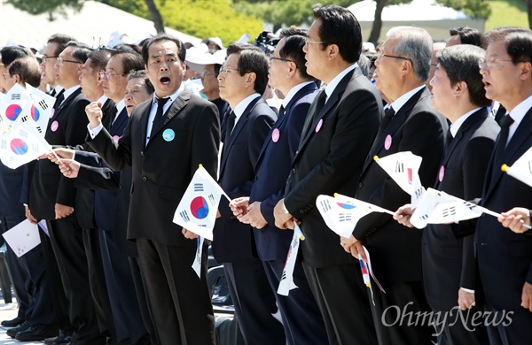 지난 18일 오전 광주광역시 국립 5.18민주묘지에서 열린 '제36주년 5.18민주화운동 기념식'에서 '임을 위한 행진곡' 기념곡 지정 및 제창 거부에 항의하는 뜻으로 참석자들이 모두 일어나 노래를 함께 부르는 가운데, 황교안 국무총리(사진 가운데)는 일어나긴 했지만 입을 다문 채 '임을 위한 행진곡'을 부르지 않고 있다.