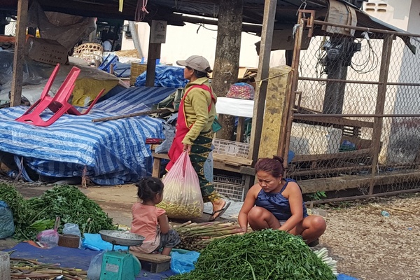 몬도가네 시장에서 엄마는 채소를 팔고 있다. 어린 아이는 혼자 놀고 있다.