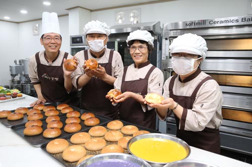 여수꽃빵의 직원들이 방금 만든 빵을 들어보이며 환하게 웃고 있다. 5월 28일 오전 모습이다.