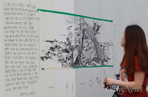  25일 오후 서울 종로구 서대문형무소 인근 옥바라지 골목 철거현장 앞을 지나가는 시민이 가림막에 적힌 재개발 반대와 골목 보존을 요구하는 글귀와 그림을 쳐다보고 있다.