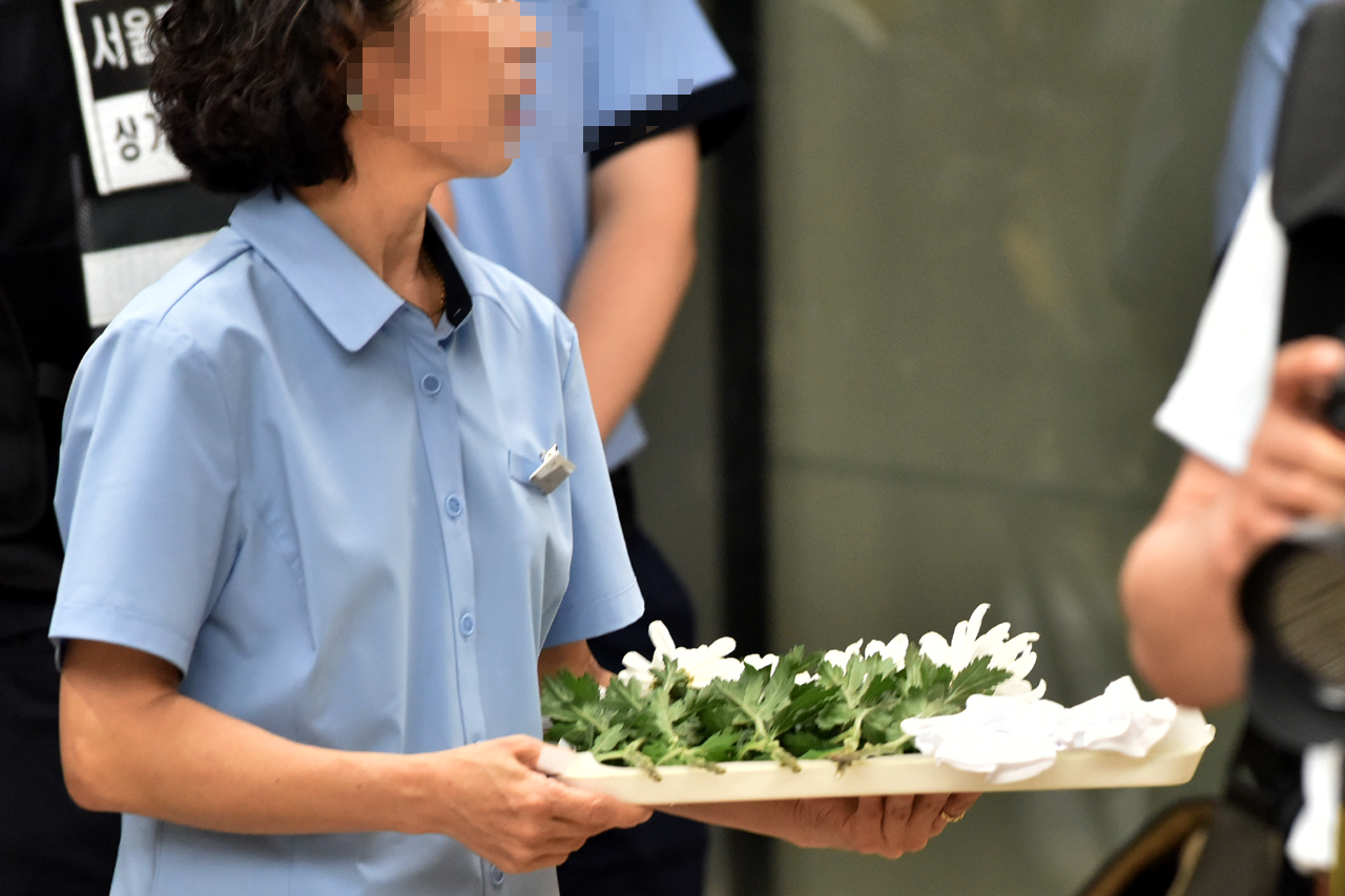  31일 오후, 구의역 스크린도어 사망사고와 관련해 각 정당소속 국회의원들의 추모행렬이 이어지고 있는 가운데 구의역에서 근무하는 한 메트로 직원이 국회의원들이 헌화할때 사용할 국화꽃을 든채 대기하고 있다.