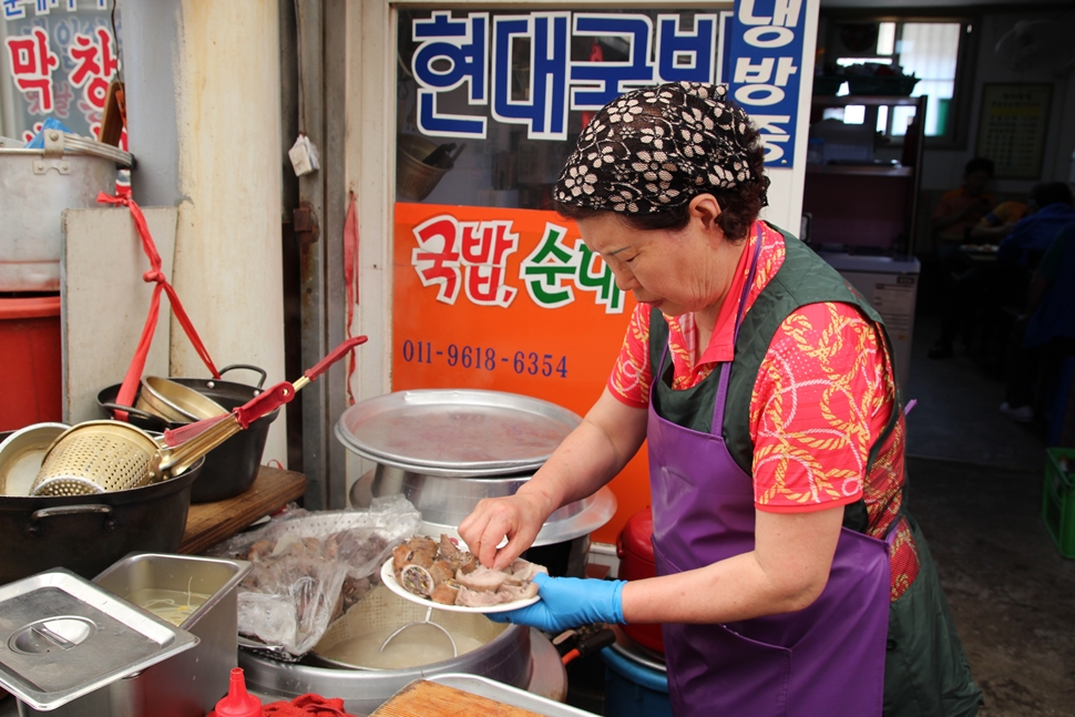 현대국밥 할머니가 음식을 정성스레 접시에 담고 있다.
