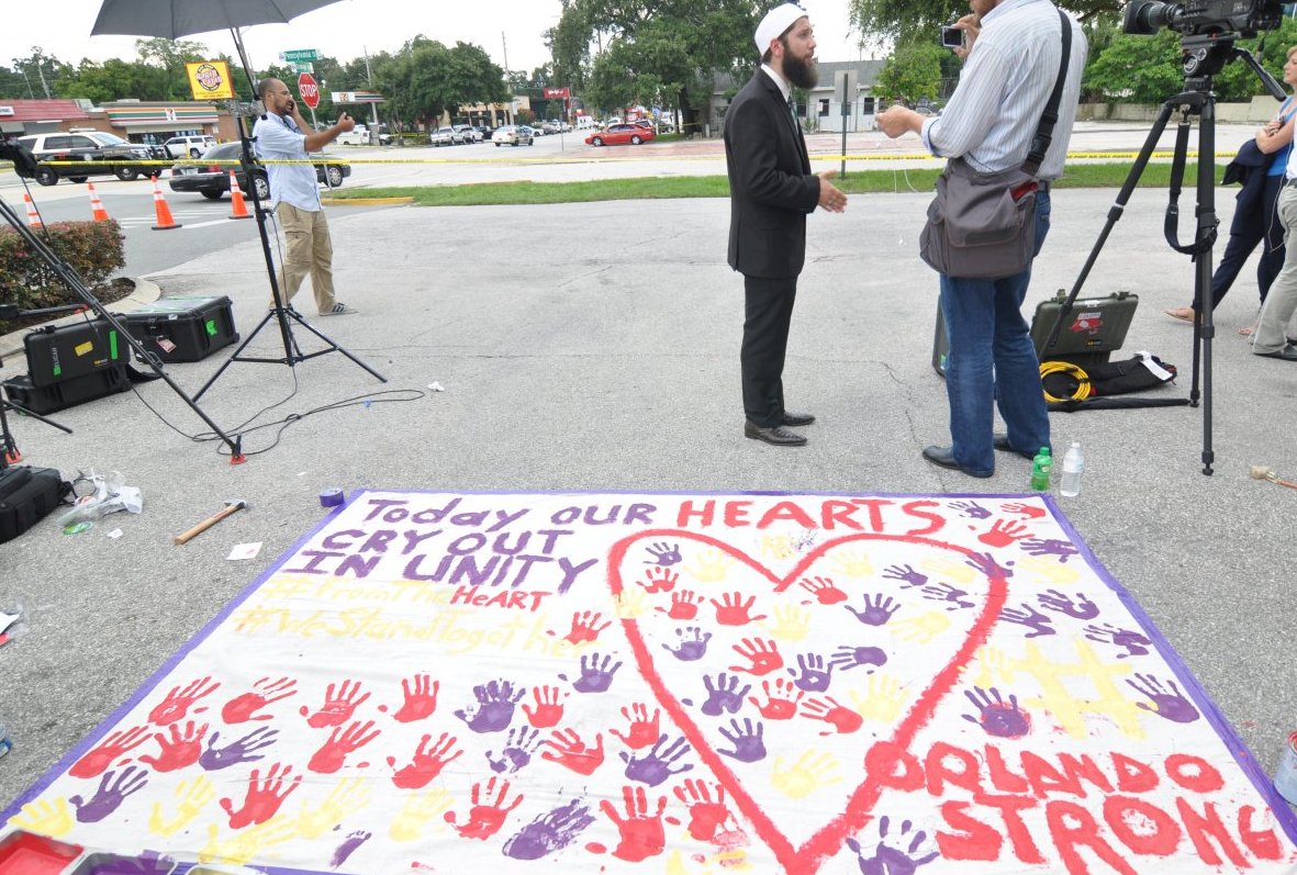 올랜도 거주하는 한 이슬람교 성직자가 기자들과 인터뷰를 하고 있다. 아래는 한 주민이 페인트로 세멘트 길바닥에 "오늘 우리 모두의 가슴은 눈물로 젖어 있다"라는 영문과 "올랜도는 강하다"라는 글귀를 써 놓았다.  