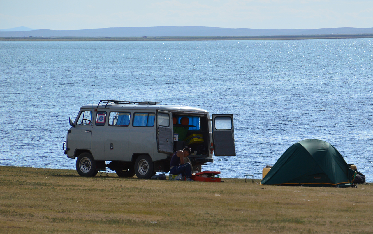 호숫가의 캠핑. 몽골의 한 젊은이가 차를 타고 와서 호숫가에서 여유 있게 캠핑을 하고 있다.