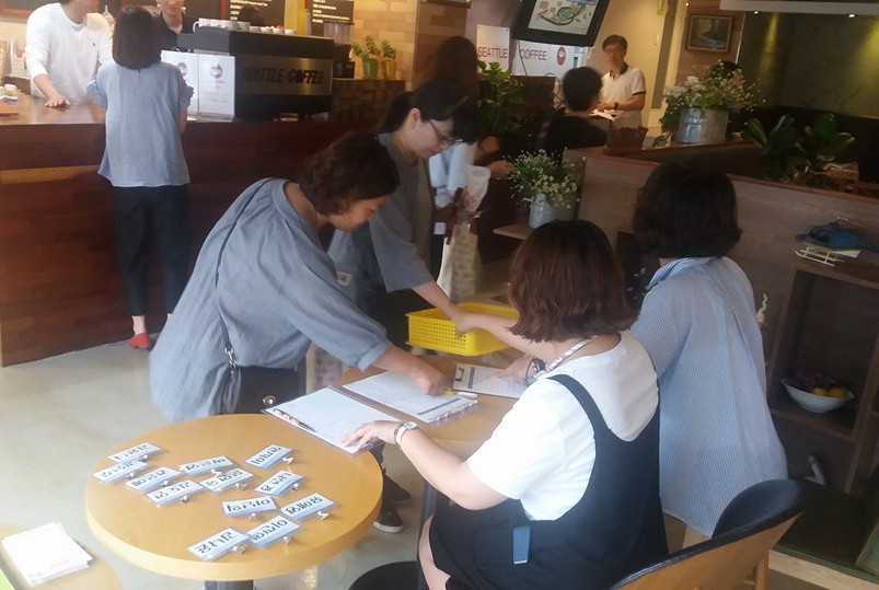    엄마들의 수다 참가자들이 테이블 번호가 적힌 쪽지를 확인하고 있다.